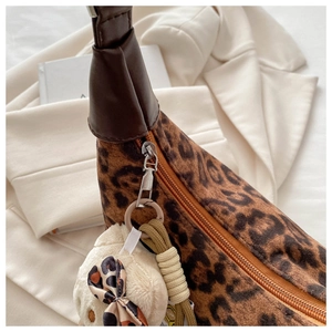 Détail du sac léopard avec bandoulière en cuir et charm peluche sur fond beige