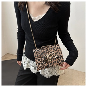 Detailed view of women's leopard print crossbody bag with gold chain strap on a model
