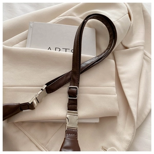 Détail d'une bandoulière de sac marron foncé avec boucle métallique argentée polie