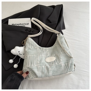 Detail of mint green bucket bag featuring a white logo tag and cute cloud plush charm