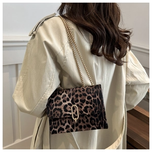 Detail of leopard print crossbody bag with gold chain strap worn with a beige trench coat