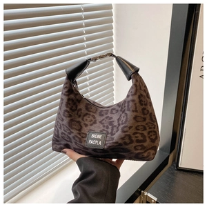 Détail du sac léopard avec texture peluche, poignée en cuir noir et étiquette logo
