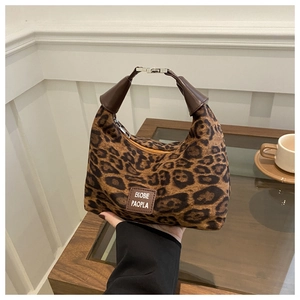 Détail d'un sac à main léopard avec poignées en cuir marron et étiquette de marque chic