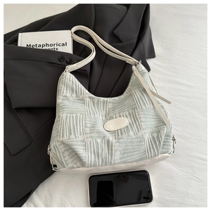 Detail of mint green textured fabric bag with white leather base and shoulder strap