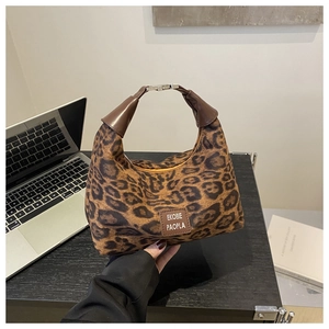 Gros plan du sac à main léopard avec poignée en cuir et détail du logo de la marque