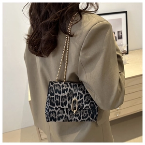 Detailed shot of leopard print shoulder bag with gold chain strap worn with a blazer