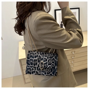 Detail der Umhängetasche mit Leopardenmuster und goldener Kette auf einem Blazer