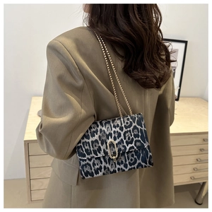 Detail of leopard print handbag with gold chain strap and oval twist lock on a shoulder