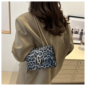 Umhängetasche mit Leopardenmuster und Goldkette am Model in minimalistischem Interieur
