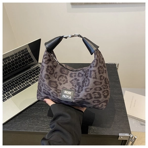 Détail du sac à main léopard avec poignée en cuir et fermoir argenté sur bureau