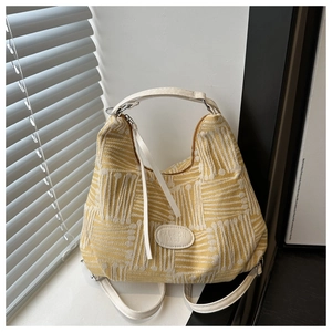 Close-up of yellow knit tote bag with leather straps and Fashion Bags patch on a window sill
