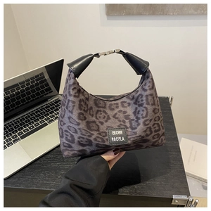 Gros plan d'un sac à main léopard en fausse fourrure avec poignée en cuir et fermoir