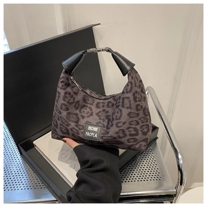 Détail du sac à main léopard avec poignée en cuir noir et fermoir métallique sur coffret