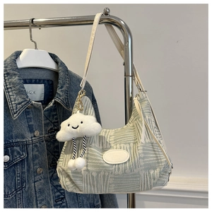 Detail of green knit hobo bag with cloud charm and fashion logo patch on denim backdrop