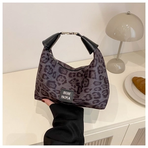 Détail du sac léopard avec poignée en cuir noir et étiquette de marque élégante