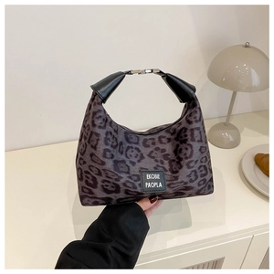 Sac hobo croissant à imprimé léopard avec poignée en cuir noir sur une table minimaliste