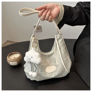 Close-up of mint green textured knit bucket bag with cream leather handle and cloud charm