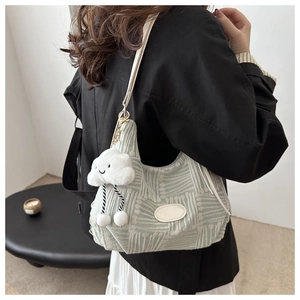 Detail of green plaid tote bag with cute cloud plush charm shown on a model's shoulder