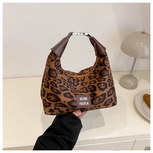 Détail du sac à bandoulière léopard avec écusson logo et texture en fausse fourrure