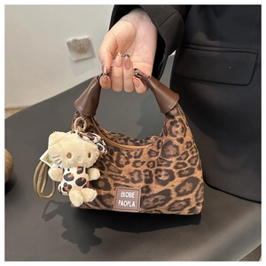 Détail du sac à main imprimé léopard avec poignée marron et pendentif chaton en peluche