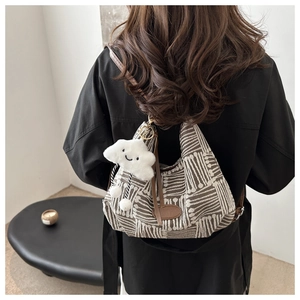 Detail of fabric tote bag with geometric patterns, leather straps and plush cloud charm