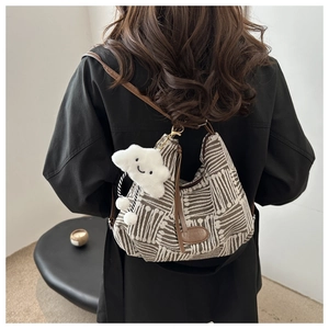 Detail of jacquard canvas bag with leather patch, featuring a white cloud charm accessory