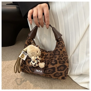Détail du sac léopard avec pendentif chat en peluche et poignée en cuir marron