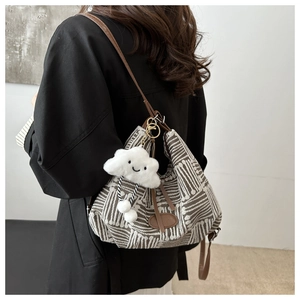 Detailed view of large shoulder bucket bag with geometric jacquard and plush charm