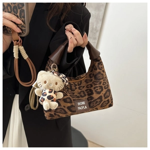 Détail d'un sac hobo léopard avec écusson en cuir et pendentif chat en peluche doux
