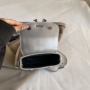 Silver metallic crossbody bag with bow accent shown open to display interior capacity