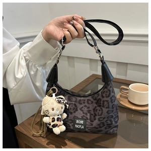Détail du sac léopard avec plaque logo et pendentif en peluche sur une table