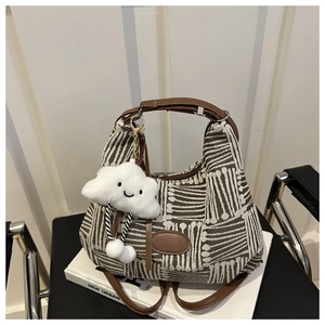 Detail of striped canvas bucket bag with leather handles and cloud plush charm