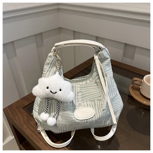 Detail of light green woven bucket bag with white handles and cute plush cloud charm