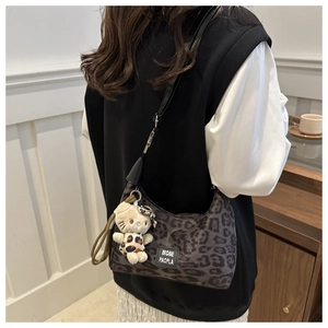 Détail du sac à bandoulière léopard avec un pendentif chat en peluche et étiquette tissée