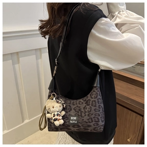 Détail du sac à main léopard avec charm chat en peluche et étiquette de marque