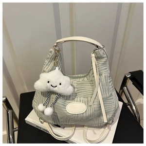 Detail of light green woven bucket bag with white leather straps and cloud charm