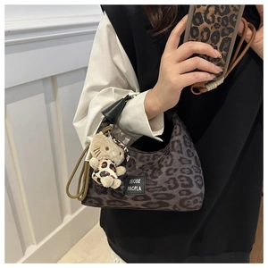 Détail du sac léopard avec breloque chat en peluche et poignée en cuir noir élégant