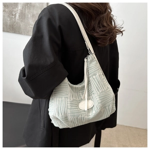 Detail of light green jacquard hobo bag with white leather strap and oval embossed logo