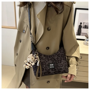 Sac à bandoulière léopard chic avec pendentif ours, porté avec un trench-coat kaki élégant