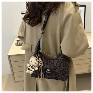 Sac à bandoulière léopard avec pendentif ours sur un trench-coat kaki élégant