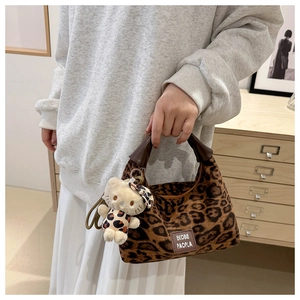 Détail du sac à main imprimé léopard avec breloque chat et lettrage de marque