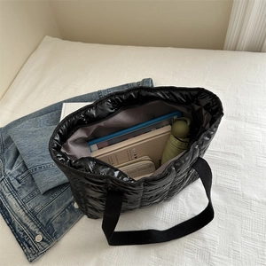 Quilted black puffer tote bag showing spacious interior with tablet and umbrella inside