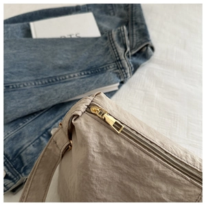 Detail of beige wrinkled nylon fabric and gold metal zipper on a large tote bag