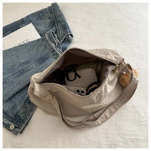 Detail of beige tote bag showing spacious interior with phone, wallet and umbrella