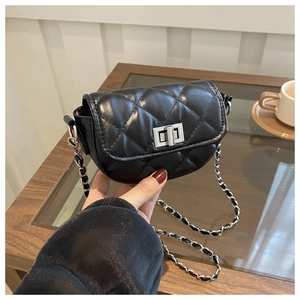 Close-up of black quilted mini bag with silver twist lock and woven chain strap