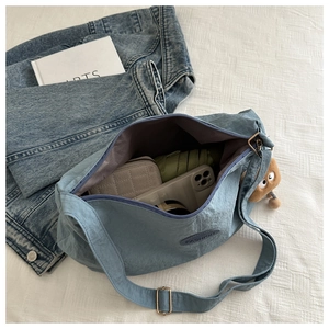 Interior storage view of a light blue nylon tote bag showing phone, wallet and umbrella