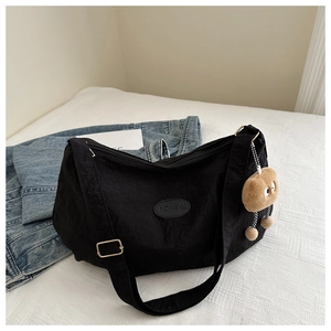Detail of black nylon tote bag with fashion patch, adjustable strap and plush charm