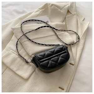 Détail d'un mini sac matelassé noir avec bandoulière chaîne sur veste crème