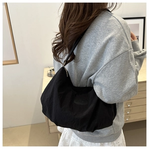 Side view of black nylon crescent shoulder bag showing large capacity and fashion label