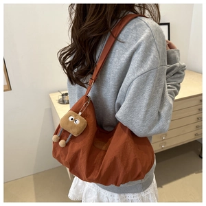Close-up of caramel nylon tote bag with plush bread charm and soft pleated texture